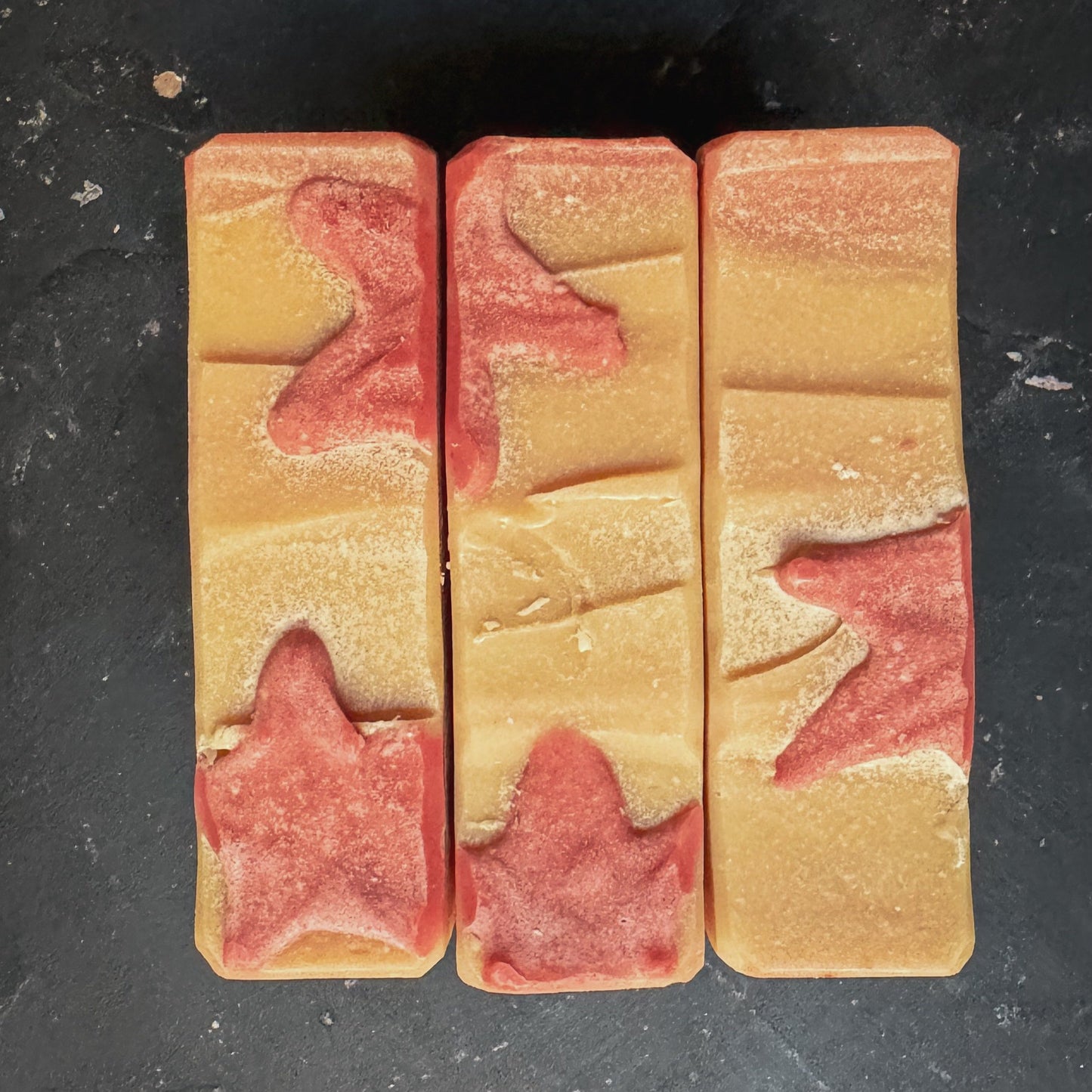 A top down view of 3 off white soap bars embellished by hand with red soap stars