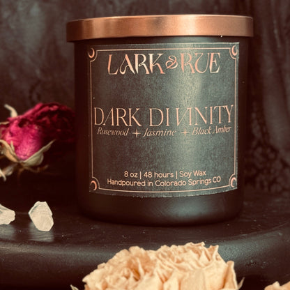 Dark Divinity candle close up with dried roses on dark background.