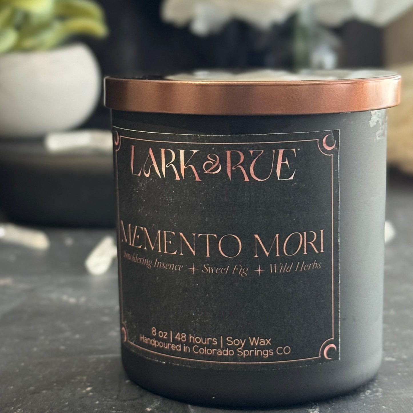 Memento Mori candle close up with blurred floral elements in background.