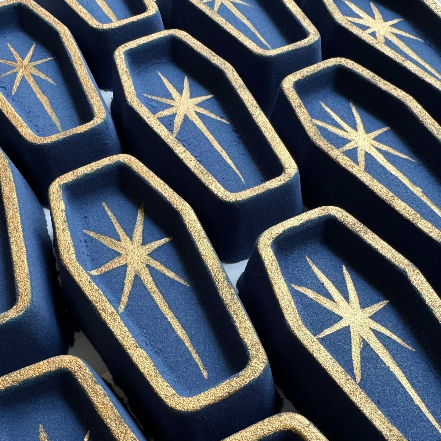 Image of several navy blue coffin bath bombs with handpainted star.