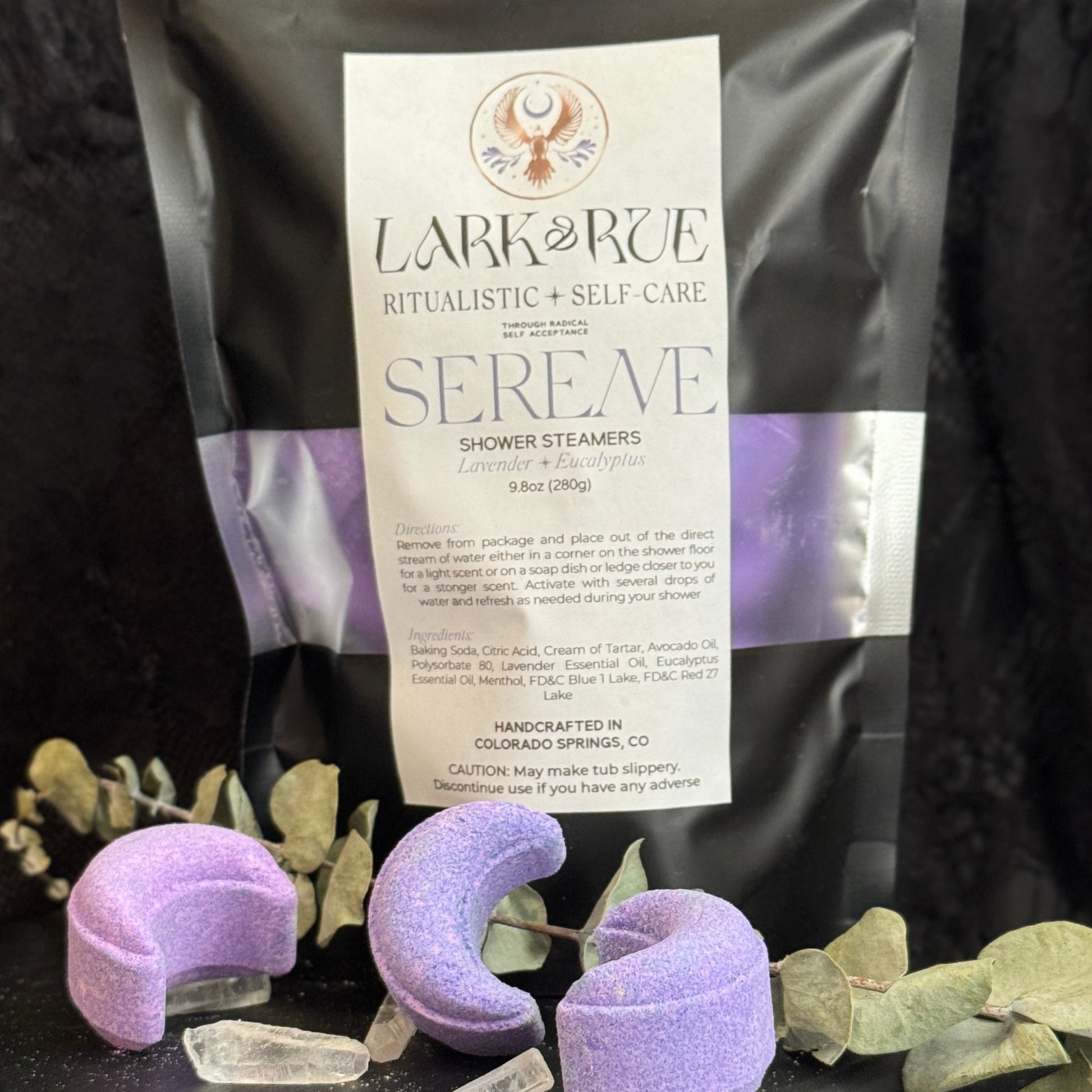 Image of black pouch filled with light purple crescent moon shower steamers on dark background.