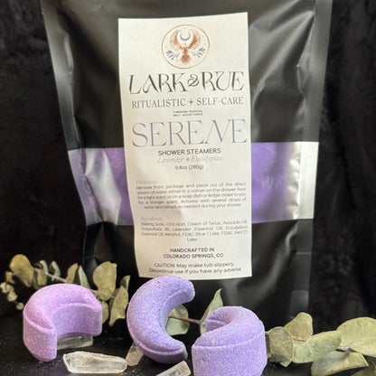 Image of black pouch filled with light purple crescent moon shower steamers on dark background.