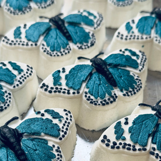 Image of white butterfly bath bombs with wings painted a dark teal and black.