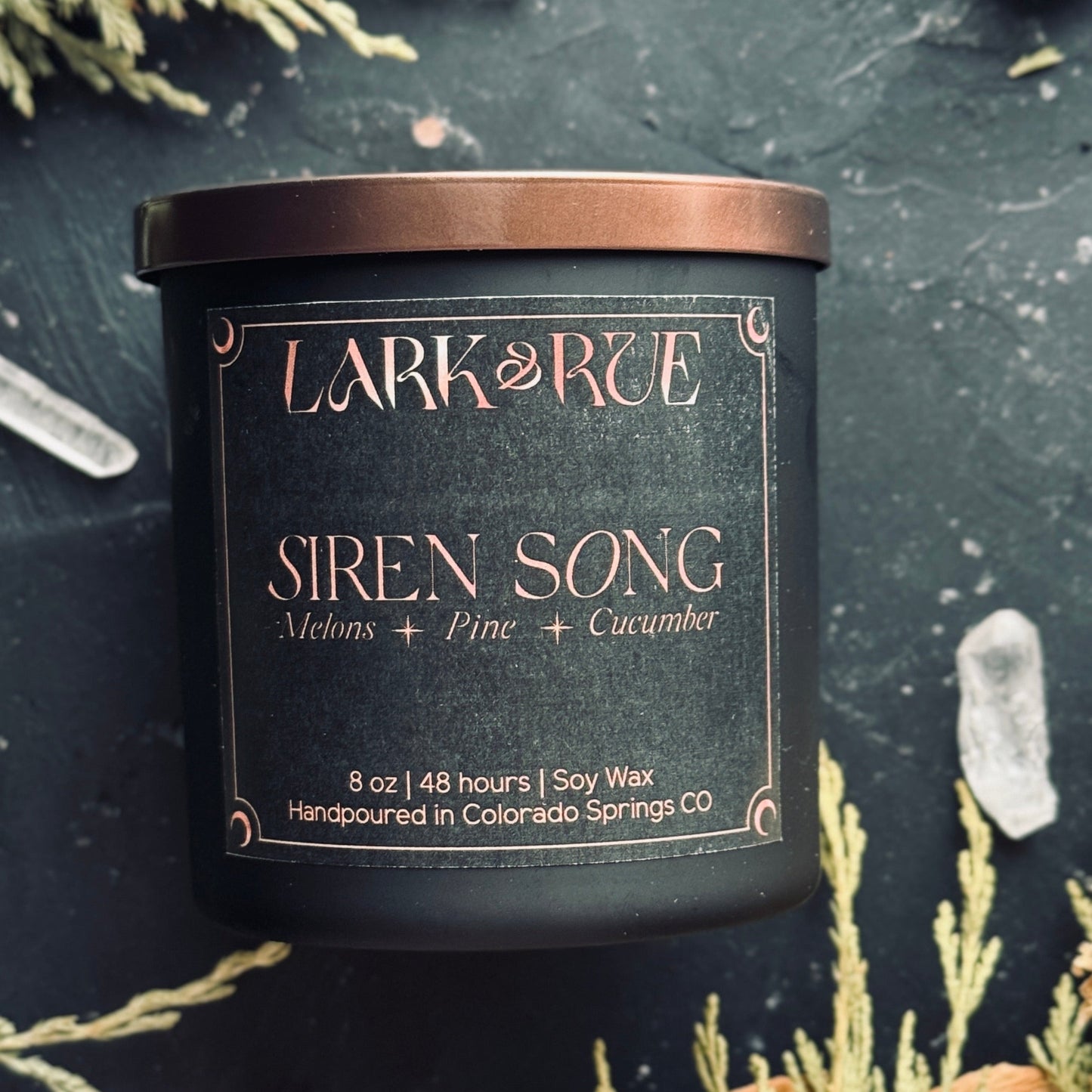Lark & Rue Siren Song candle with natural elements on a dark background