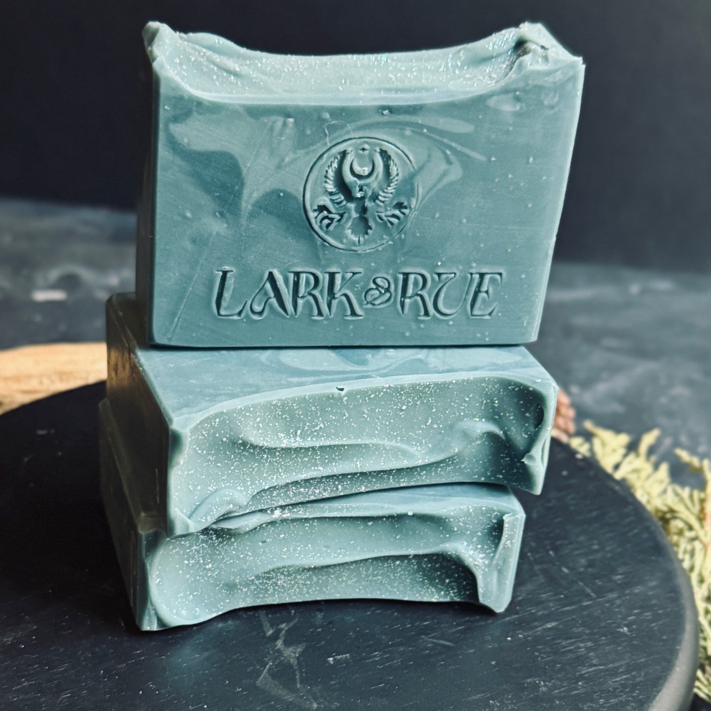A stack of Siren Song soaps featuring a front view of the deep teal soap swirling through lighter ocean hues.